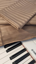Close-up of a piano with a brown striped fabric draped over it. Duvet cover
