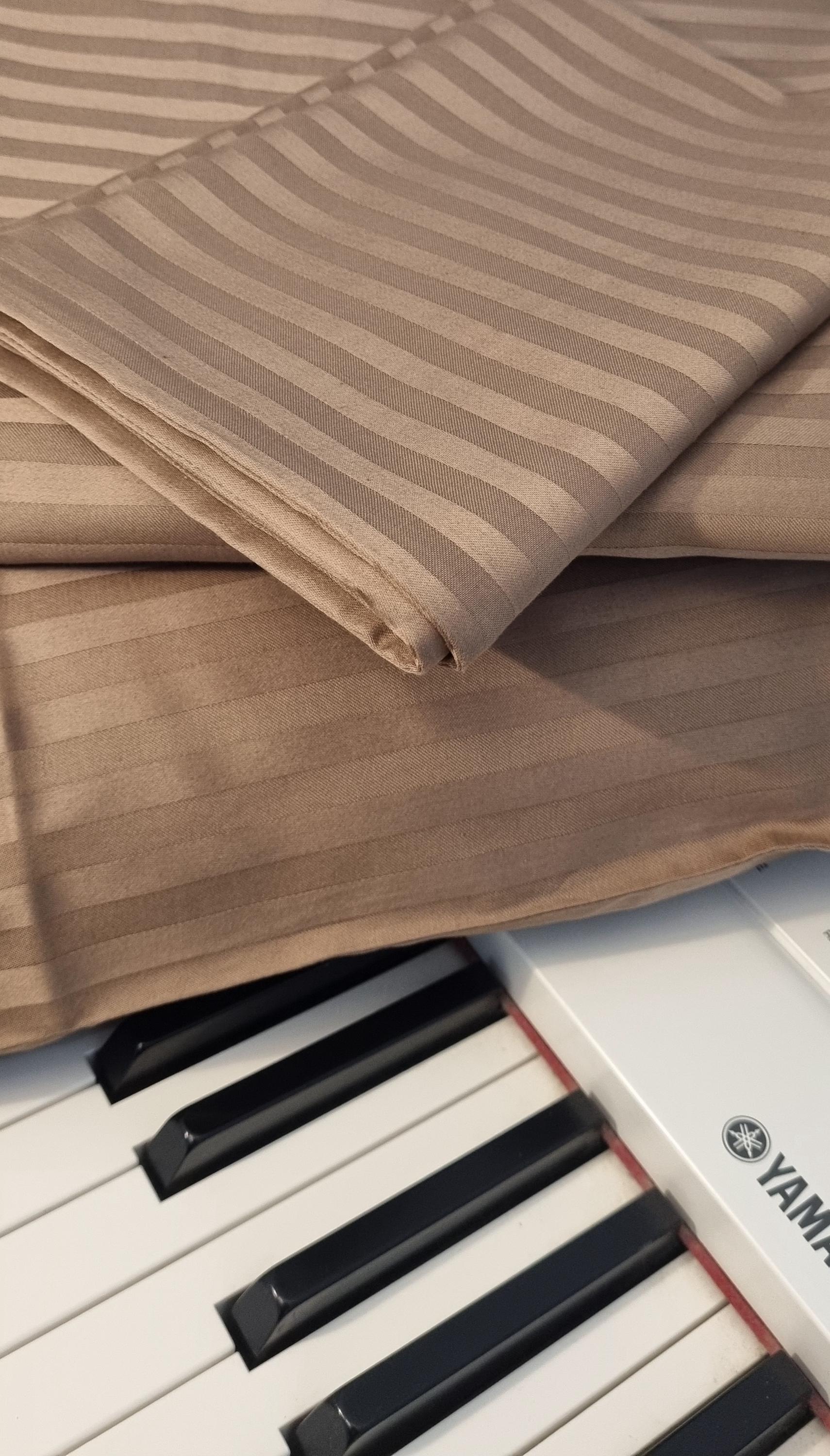 Close-up of a piano with a brown striped fabric draped over it. Duvet cover
