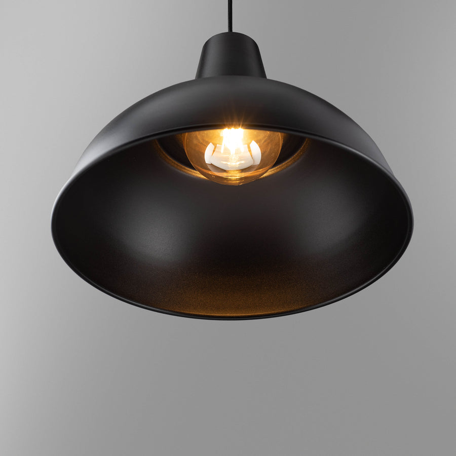 Foundry black pendant light lit, warm glow